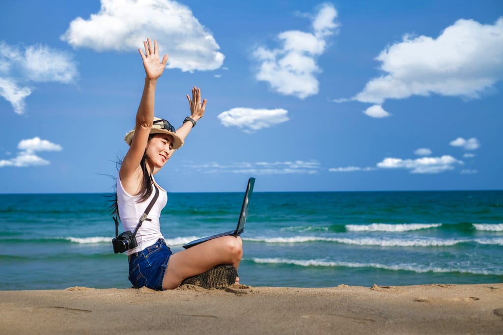 Asian woman sitting at the beach using latop