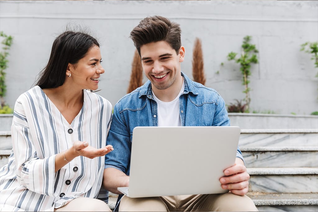 Man and woman using laptop outside