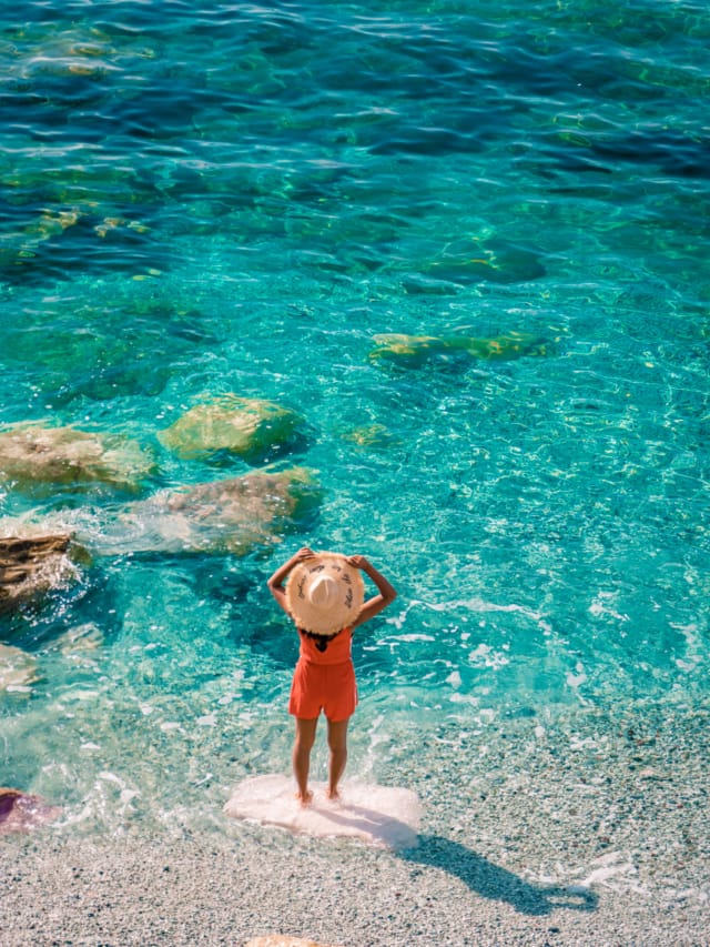 Young,Woman,Walking,At,Pebble,Beach,Monterosso,On,Vacation,Cinque