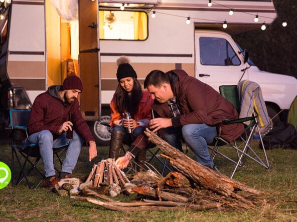 Group Starting a Campfire Outside Their RV