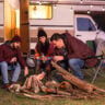 Group Starting a Campfire Outside Their RV