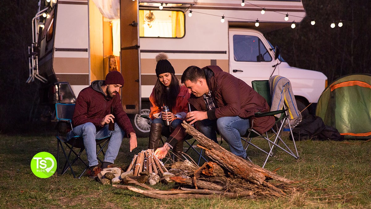 Group Starting a Campfire Outside Their RV